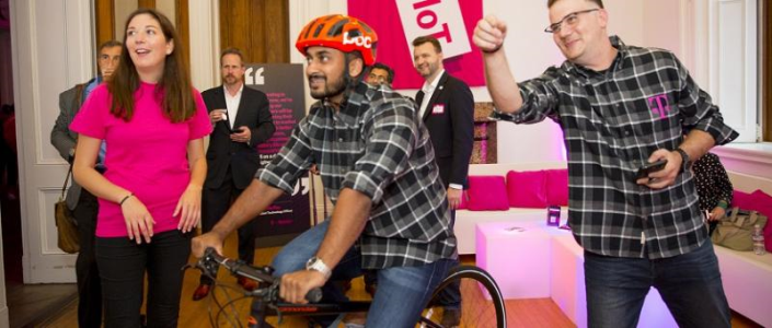 Event attendee riding a stationary bike while wearing a smart helmet as other attendees watch in the background